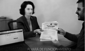 Documento de alvará de funcionamento fixado na parede de entrada de um estabelecimento comercial regularizado.