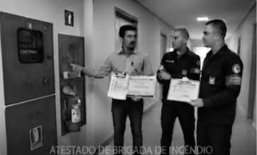 Profissionais participando de treinamento prático de brigada de incêndio utilizando extintores em área segura.